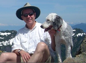 Hiker with dog on snowy mountain ridge